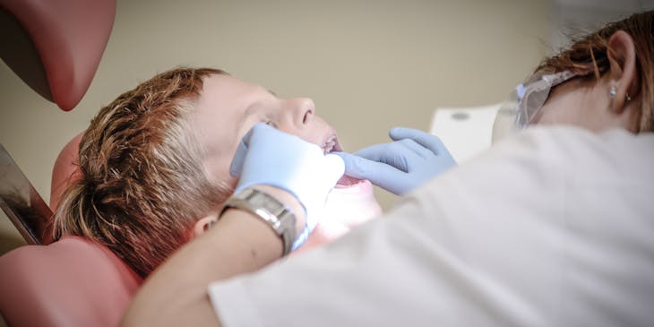 Pediatric dentist performing dental work on a patient.