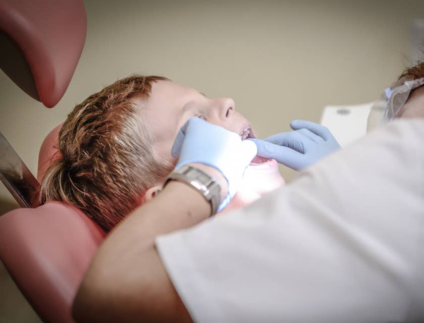 Dentista pediátrico examinando uma criança em uma clínica de odontopediatria.