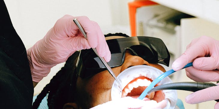 A periodontist treats a patient who is donning protective eyewear.