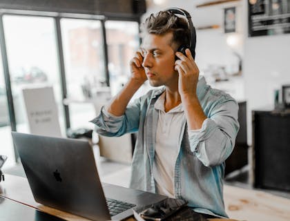 Un asistente personal tomando una llamada telefónica y usando su computadora portátil en su oficina en un negocio de asistentes personales.