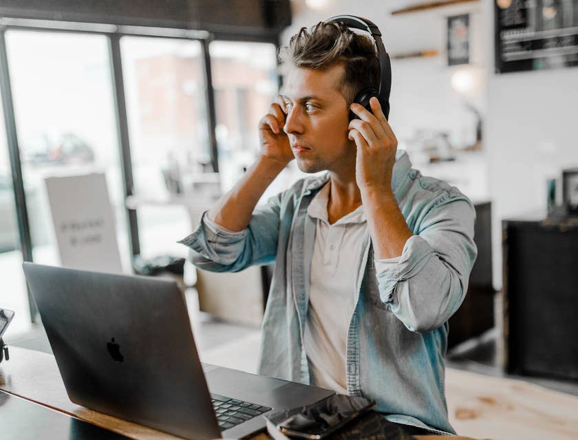 Ein persönlicher Assistent sitzt in einem Büro vor einem Laptop und trägt Kopfhörer, um einen Anruf entgegenzunehmen.