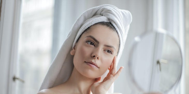 Woman touching face and looking in a mirror.
