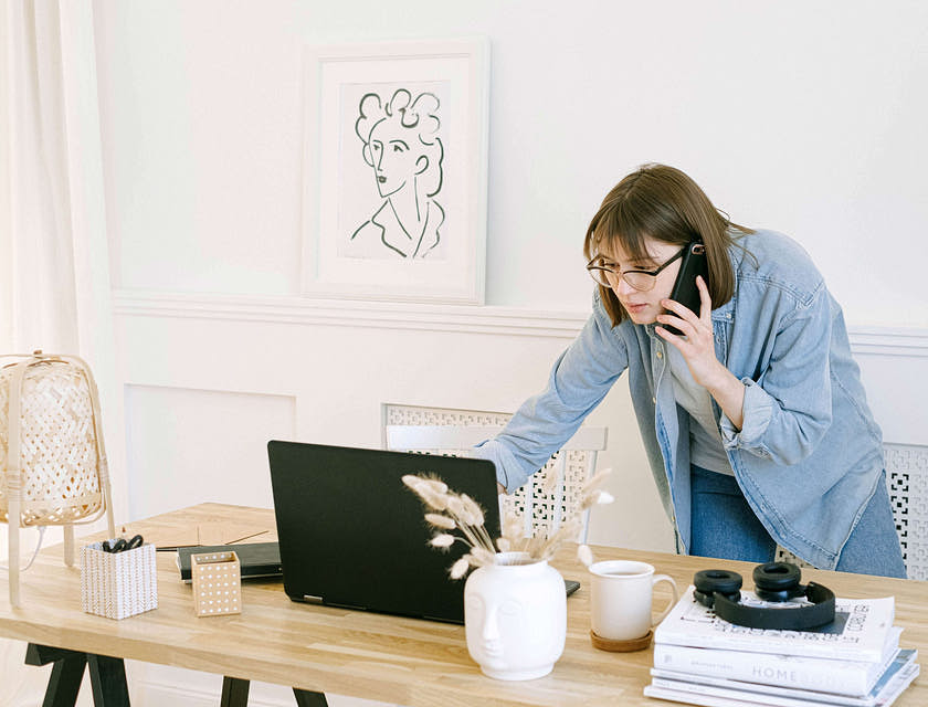 A personal concierge checking her laptop while talking on the phone.