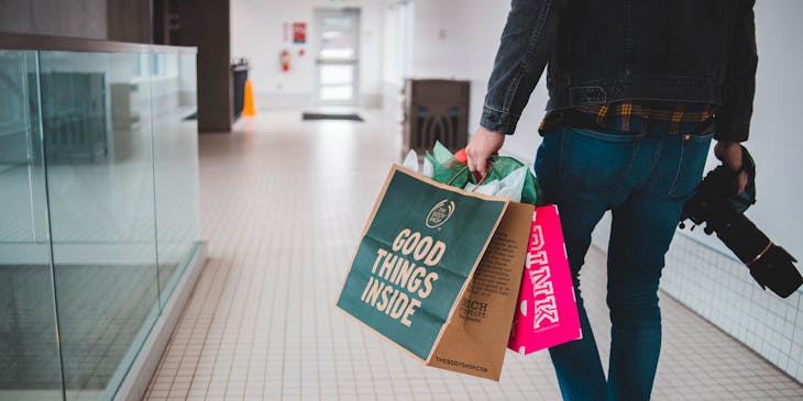 A personal shopper carrying shopping bags while walking through the mall.