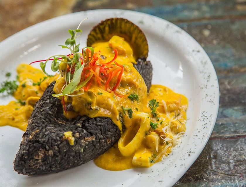 Un piatto di specialità peruviana di riso nero con calamari in salsa gialla.