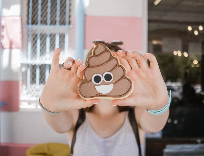 Una persona che effettua un servizio di raccolta di feci di animali domestici che mostra un biscotto a forma di emoji della cacca.