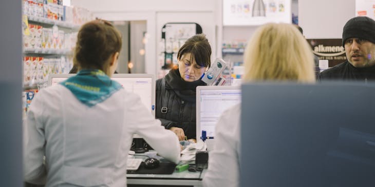 A woman purchasing medication from a pharmacist.