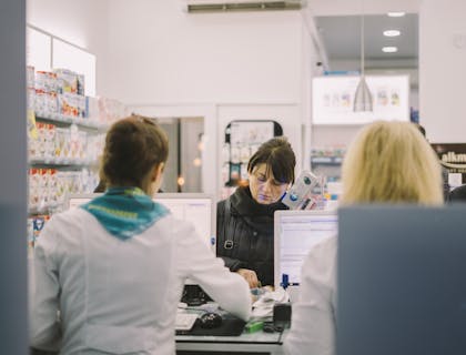 Mulher comprando medicamento de um farmacêutico.