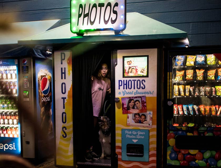 Una ragazza che sta uscendo da un photo booth insieme al suo cane.