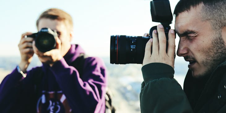 Two men holding up cameras.