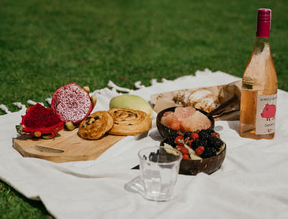 A picnic prepared by a picnic business spread out on a blanket on grass.