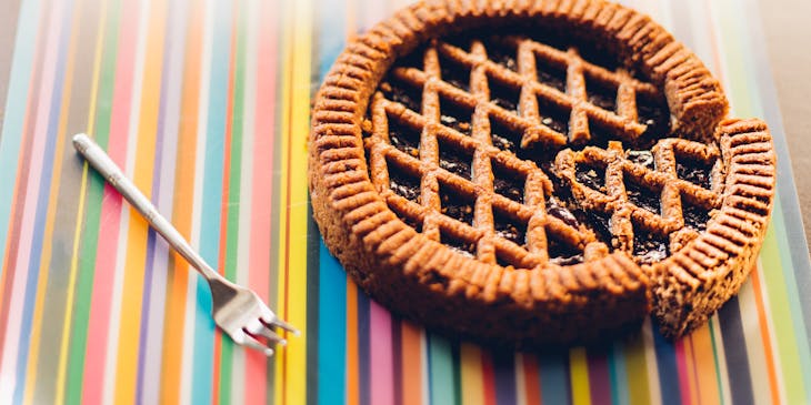 Una crostata tagliata su una tovaglia colorata con accanto una forchetta.
