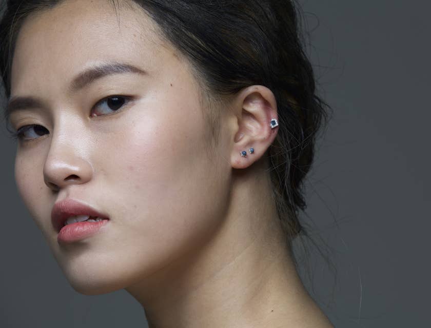 Une modèle asiatique montrant les piercing de ses oreilles.