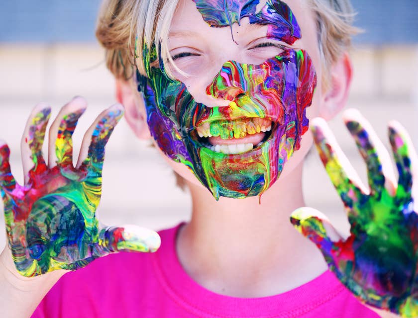 Un niño juguetón con pintura en la cara, los dientes y las manos.