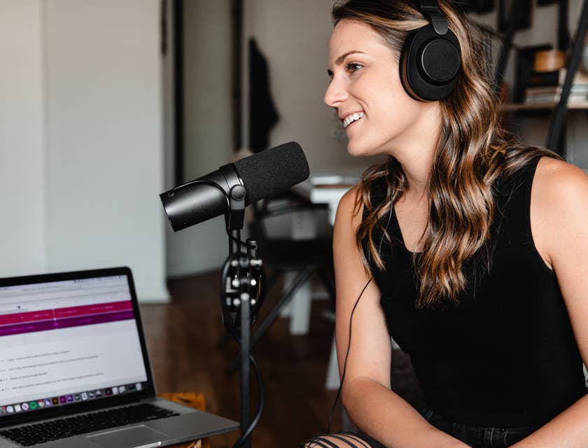 Une femme avec des écouteurs et un microphone dans une pièce enregistrant un podcast.