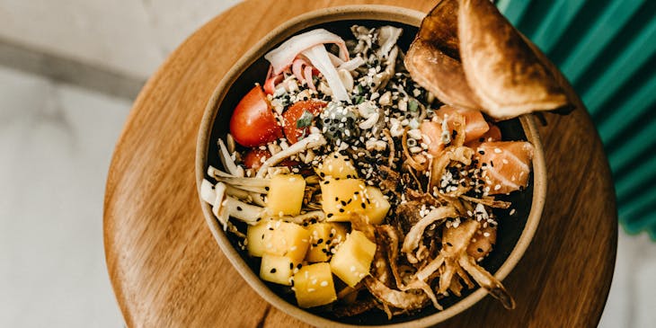 Poke bowl with fish and vegetables and two chopsticks at a poke business.