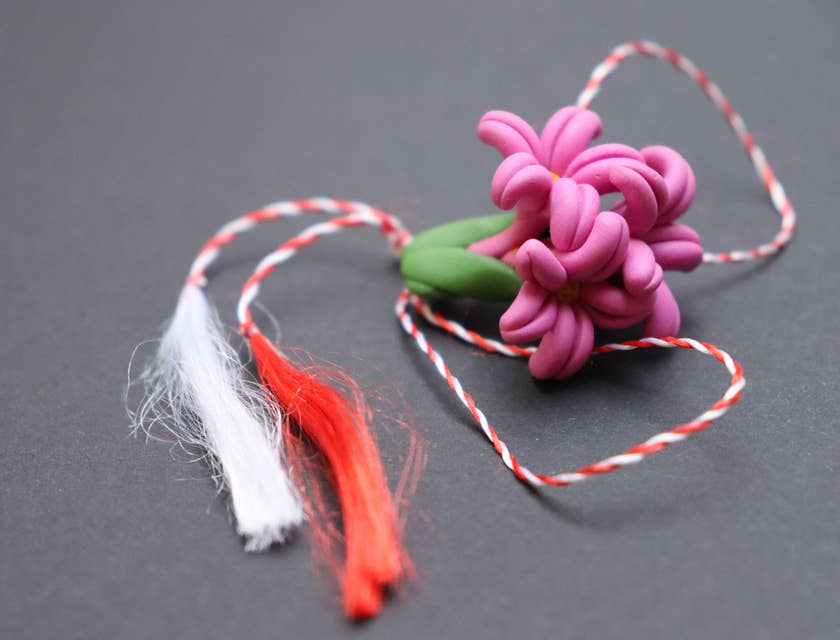 Eine modellierte, rosafarbene Blume aus Polymer-Ton an einem rot-weißen Faden.