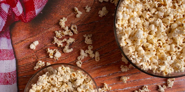 Popcorn in bowls on a table with scattered popcorn.