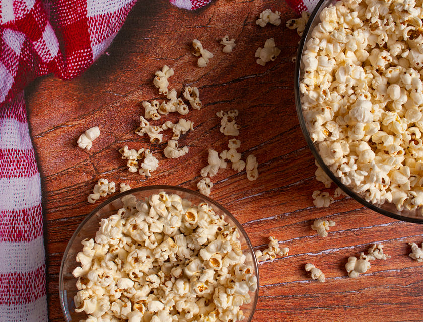 Zwei Schüsseln mit Popcorn stehen auf einem Holztisch.