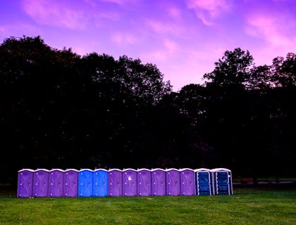 A line of portable toilets in a field.