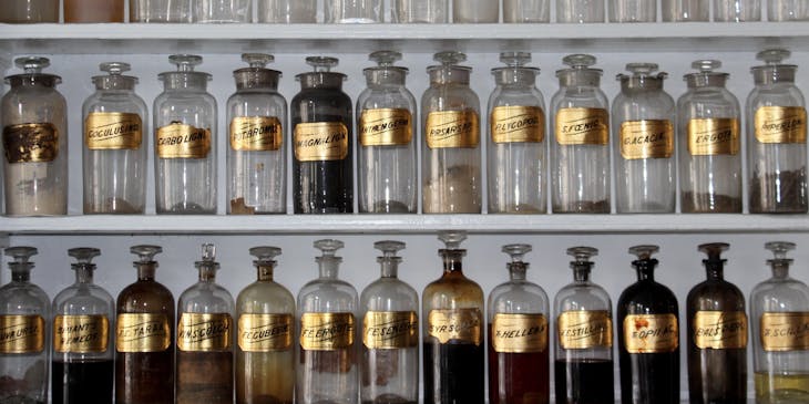 Clear glass jars filled with powder sitting on shelves in a potion shop.