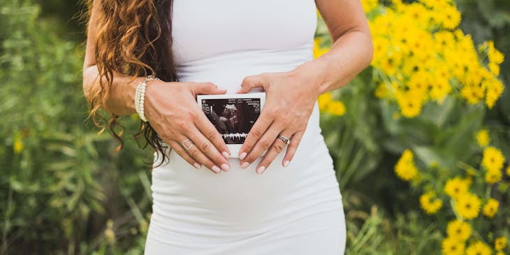 A pregnant woman showing a picture of her ultrasound as part of her prenatal/perinatal care.