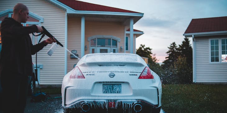 Man pressure washing car