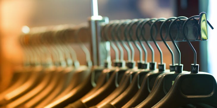 Black shirts on black hangers on a rail.