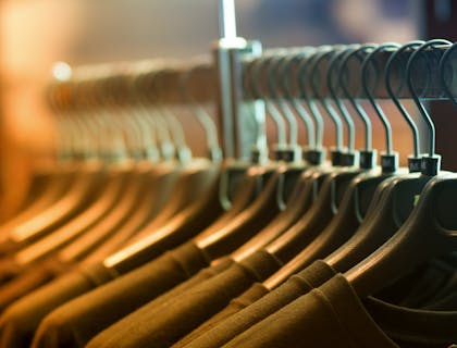 Black shirts on black hangers on a rail.
