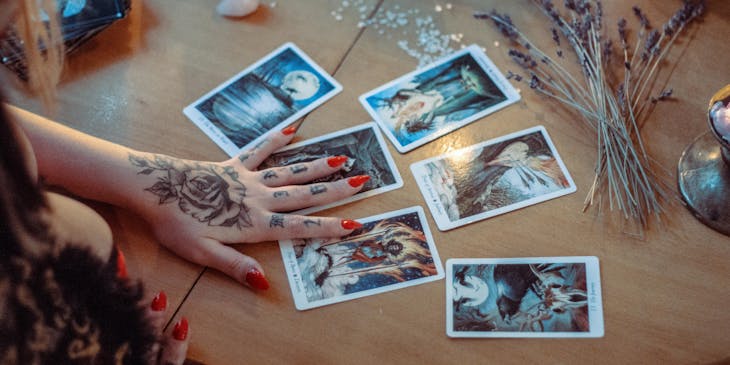 A psychic reading tarot cards on a table with lavender and crystals.