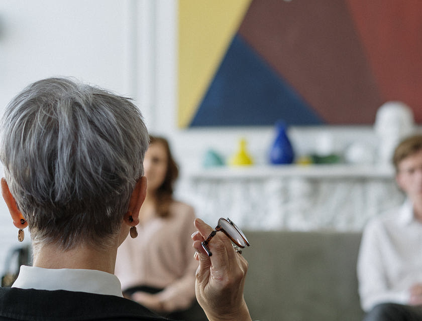 Seated woman facing a man and another woman during therapy.