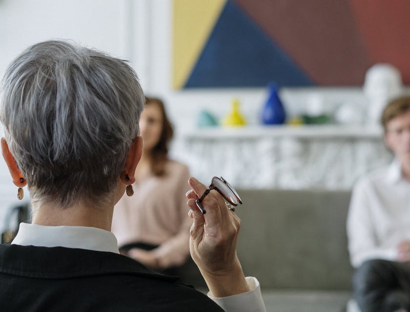 Seated woman facing a man and another woman during therapy.