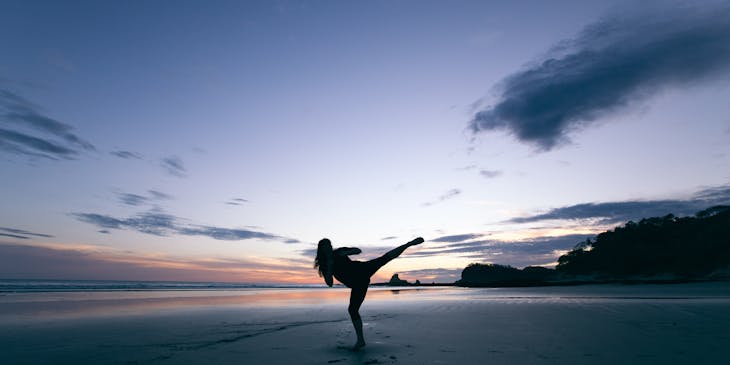Woman practicing qi gong on a beach.