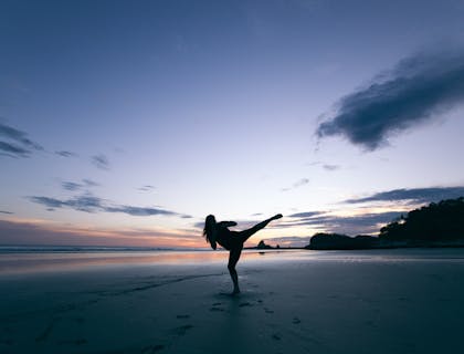Woman practicing qi gong on a beach.
