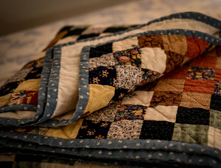Eine bunte, aufgeschlagene Patchwork-Decke aus einem Quilt-Geschäft liegt auf einem Bett.