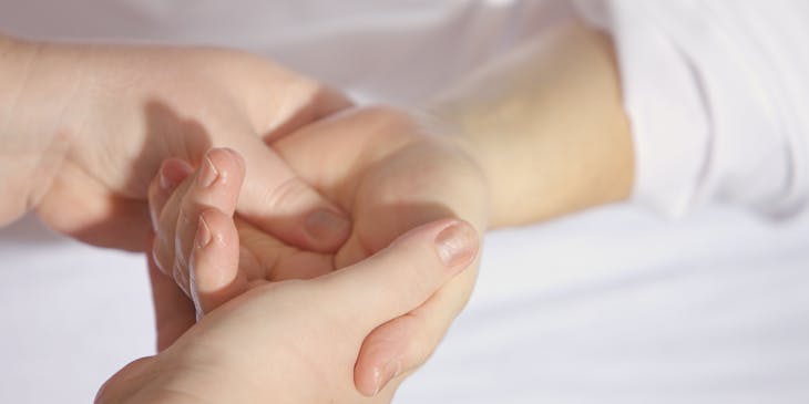Someone using reflexology to massage a woman's palm.