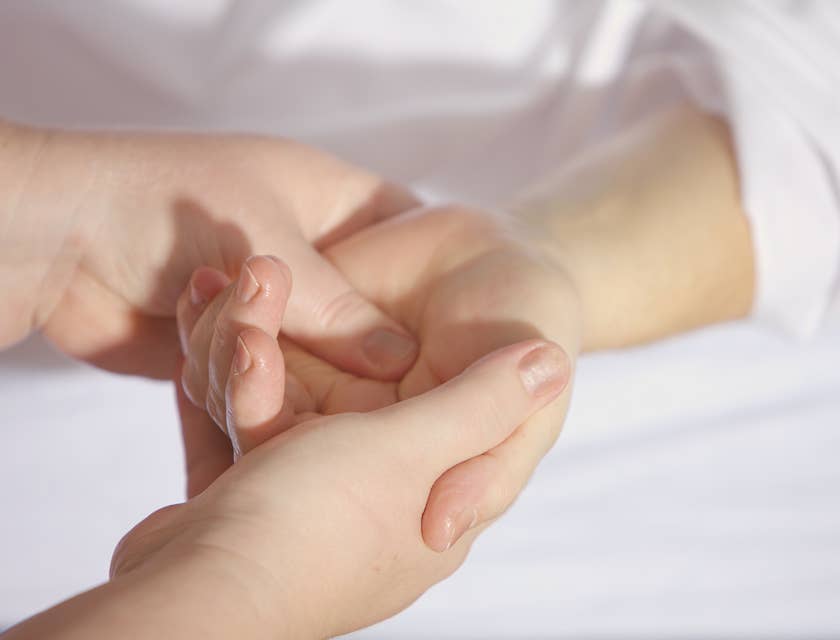 Un riflessologo che massaggia il palmo della mano di un paziente.