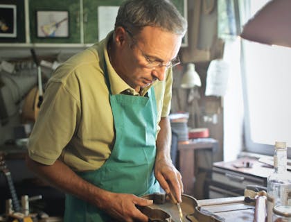 A man carefully repairing a violin.