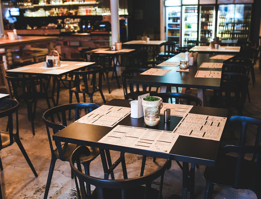 An empty restaurant with placemats on tables.