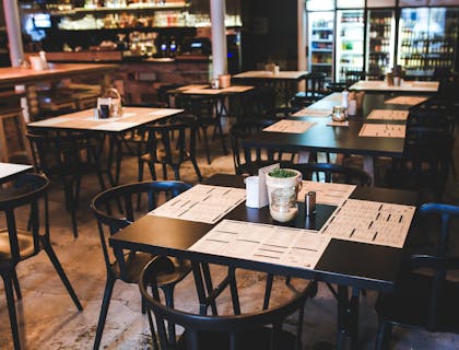 An empty restaurant with placemats on tables.