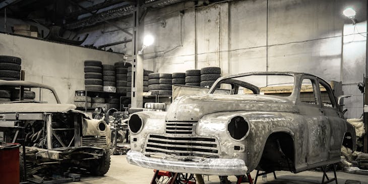 Body of an old car on jack stands at a car restoration business.