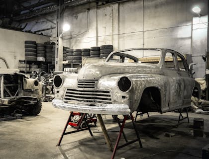 Body of an old car on jack stands at a car restoration business.
