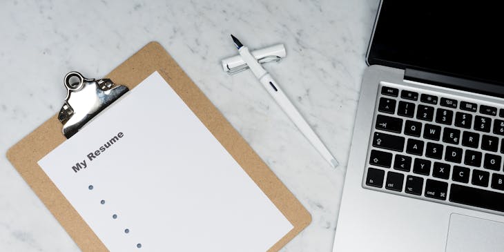 White printed paper with "My Resume" as the heading beside a silver laptop and a white pen.