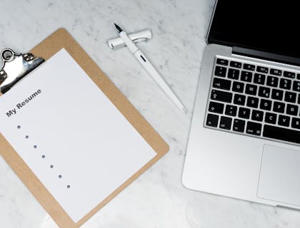 White printed paper with "My Resume" as the heading beside a silver laptop and a white pen.
