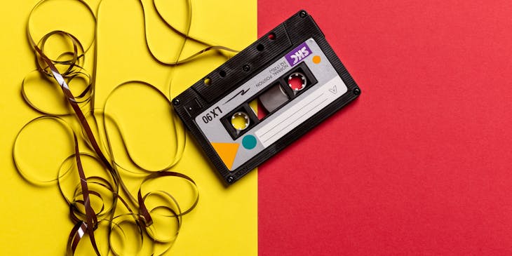 Black cassette tape on a retro yellow and red background.