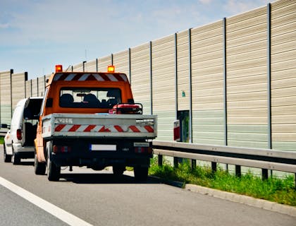 Un vehículo de asistencia en el camino ayudando a un coche averiado.