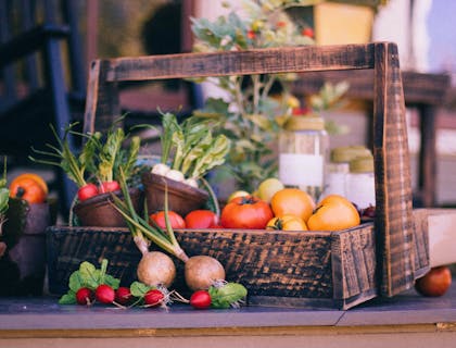 Una canasta rústica con varias verduras de temporada en un mercado local.