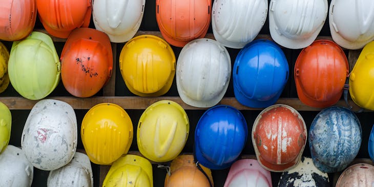 Hard hats stacked in a wire rack.