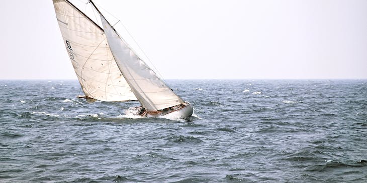 A sailboat roll tacking while sailing on choppy waters.