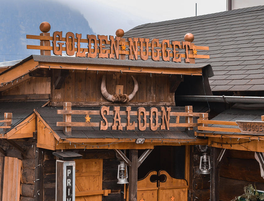 Façade d'un vieux bâtiment avec les mots "Golden Nugget Saloon" accrochés au mur.